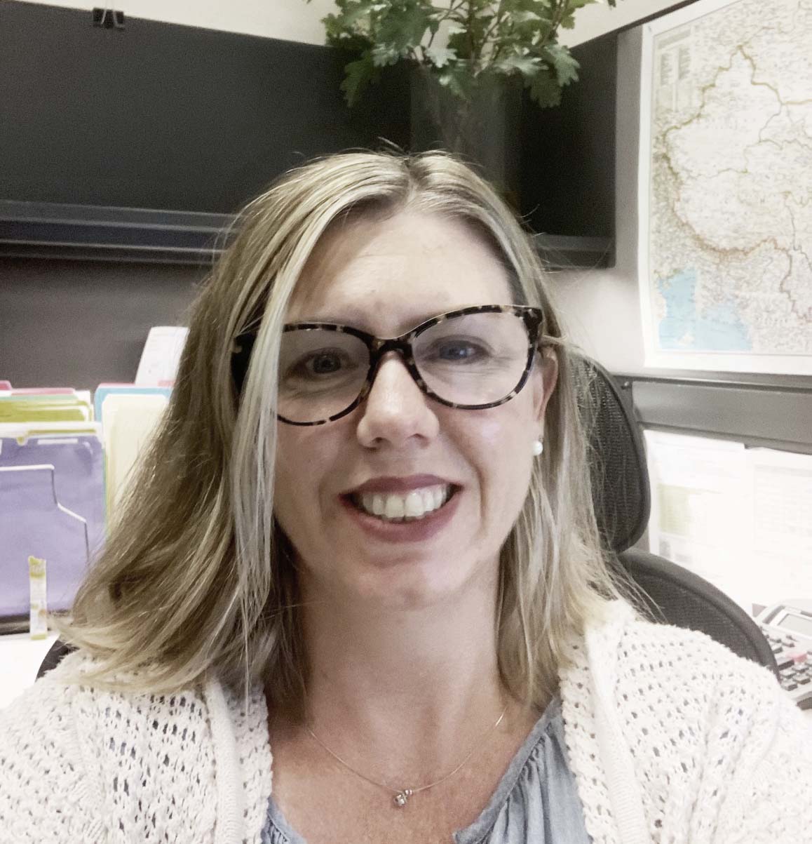 Portrait of a middle-aged woman wearing glasses in an office.