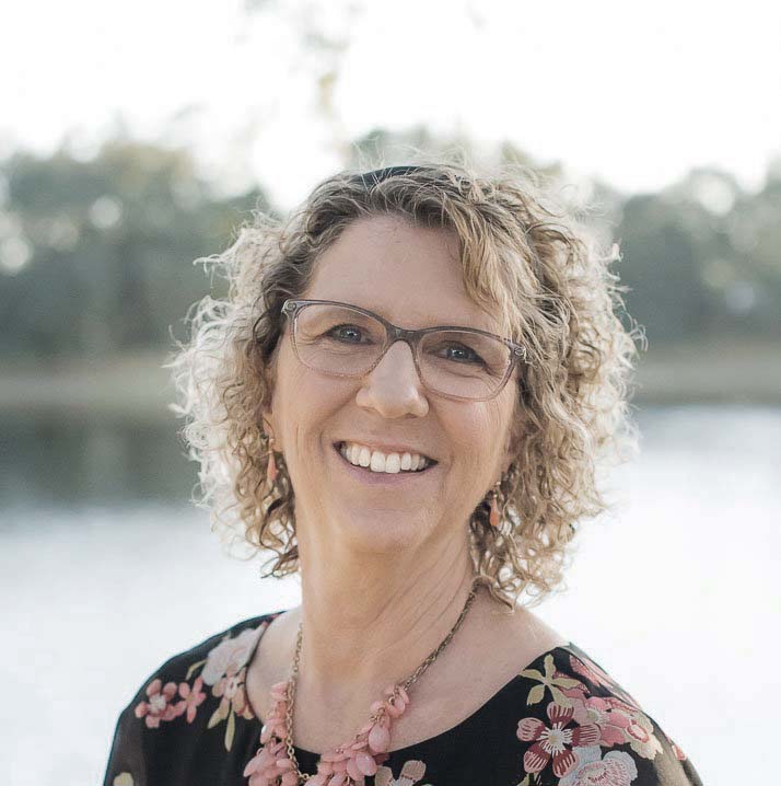 Portrait of woman with glasses and curly in front of a lake